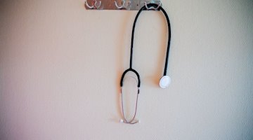 Ein Stethoskop hängt in einem Krankenhaus an einer Garderobe. / Foto: Christoph Soeder/dpa/Symbolbild