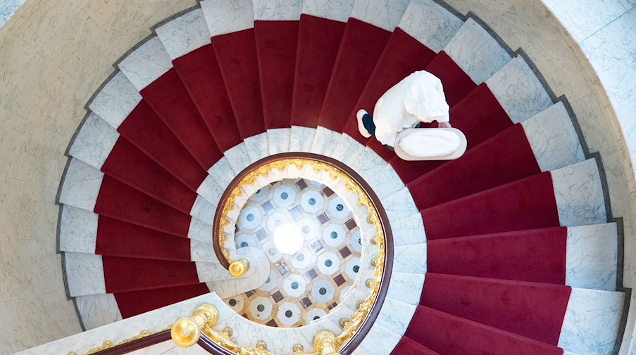 Andreas Wippler, maestro panadero, sube un stollen por una escalera de caracol / Foto: Sebastian Kahnert/dpa