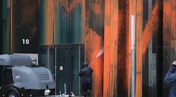 Ein Mitarbeiter einer Reinigungsfirma säubert die Fassade eines Gebäudes der Universität Leipzig. / Foto: Sebastian Willnow/dpa