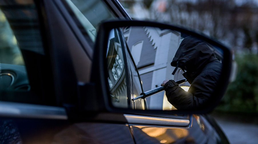 Ein Mann versucht eine Autotür mit einer Metallstange aufzubrechen (gestellte Szene). / Foto: Axel Heimken/dpa/Archivbild