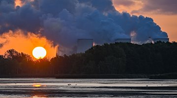 Der Sonnenaufgang scheint hinter dampfenden Kühltürmen des Braunkohlekraftwerks Jänschwalde der Lausitz Energie Bergbau AG (LEAG). / Foto: Patrick Pleul/dpa