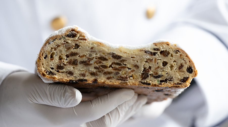 Ein Prüfer hält einen Christstollen in der Hand. / Foto: Sebastian Kahnert/dpa