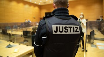 Ein Justizbeamter steht in einem Gerichtssaal. / Foto: Friso Gentsch/dpa/Symbolbild