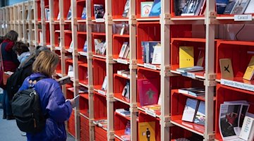 Відвідувачі Лейпцизького книжкового ярмарку гортають книги на стенді / Фото: Hendrik Schmidt/dpa