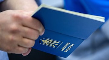 Чоловік тримає в руці український паспорт / Фото: Jens Büttner/dpa/Symbolic image