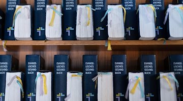 Evangelische Gesangbücher in einer Kirche. / Foto: Silas Stein/dpa/Illustration