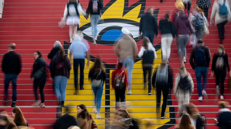 Los visitantes descienden por una escalera con el logotipo de la Feria del Libro de Leipzig al comienzo de la jornada ferial.... / Foto: Hendrik Schmidt/dpa/archive image