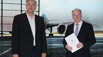 Markus Otto (l) und Reiner Haseloff (CDU) stehen im Flughafen Leipzig/Halle vor dem Plakat eines Flugzeugs. / Foto: Sebastian Willnow/dpa