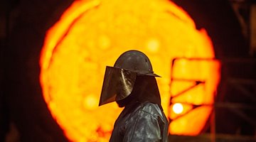 Працівник сталеливарної промисловості стоїть перед розпеченим чавунним ковшем / Фото: Christophe Gateau/dpa/Symbolic image