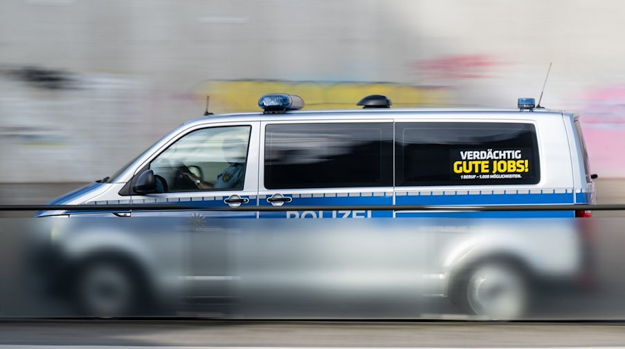 A police car with the sign "Suspiciously good jobs!" drives along a road / Photo: Robert Michael/dpa