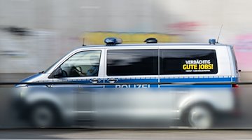 A police car with the sign "Suspiciously good jobs!" drives along a road / Photo: Robert Michael/dpa