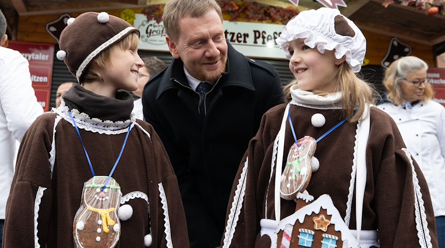 مايكل كريتشمر (CDU)، رئيس وزراء ساكسونيا، يرحب بأطفال بلسنيتز للكعك الفلفلي في ساحة السوق. / صورة: سيباستيان كانهرت / dpa