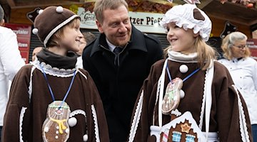 Michael Kretschmer (CDU), Ministerpräsident von Sachsen, begrüßt zur Eröffnung des 19. Pulsnitzer Pfefferkuchenmarkt die Pfefferkuchenkinder auf dem Marktplatz. / Foto: Sebastian Kahnert/dpa