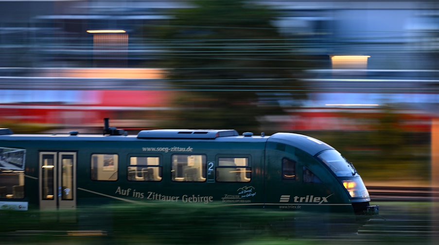 Ein Trilex Zug der Länderbahn fährt am Morgen auf einem Gleis entlang. / Foto: Robert Michael/dpa