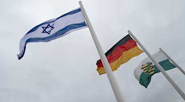 Die Fahnen von Israel (l-r), Deutschland und Sachsen wehen vor dem Sächsischen Landtag im Wind. / Foto: Robert Michael/dpa