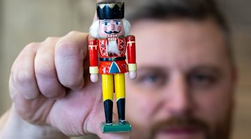 Виробник дерев'яних іграшок Маркус Фюхтнер тримає в руці міні-лускунчика Вільгельма у своїй майстерні в Зайфені / Фото: Hendrik Schmidt/dpa
