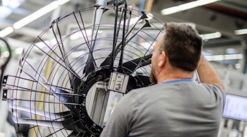 Ein Mitarbeiter eines Elektromotoren- und Ventilatorenherstellers, arbeitet in der Produktion an einem Ventilator. / Foto: Christoph Schmidt/dpa/Archivbild