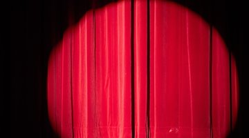 A spotlight illuminates the curtain on a stage / Photo: Sebastian Kahnert/dpa/Symbolic image