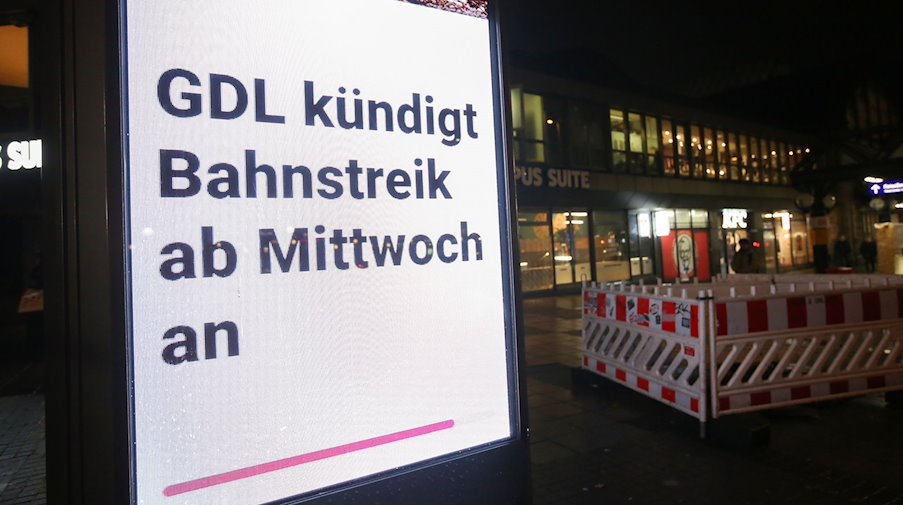 Der bevorstehende Streik der Gewerkschaft GDL wird auf einer Werbetafel vor einem Bahnhof angezeigt. / Foto: Bodo Marks/dpa