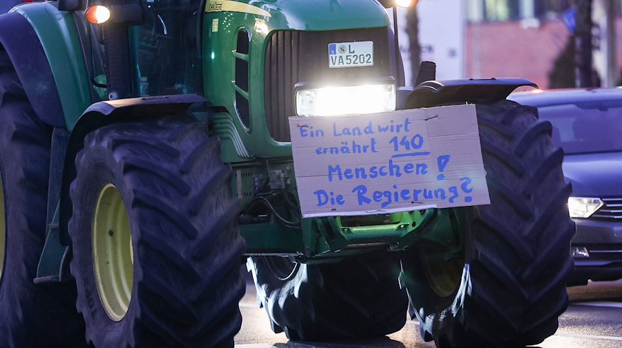 Uno de varios agricultores atraviesa el tráfico con su tractor y un cartel / Foto: Jan Woitas/dpa