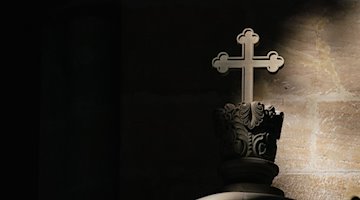 شعاع ضوء يسقط على صليب في كنيسة. / نيكولاس آرمر / دبا / صورة رمزية