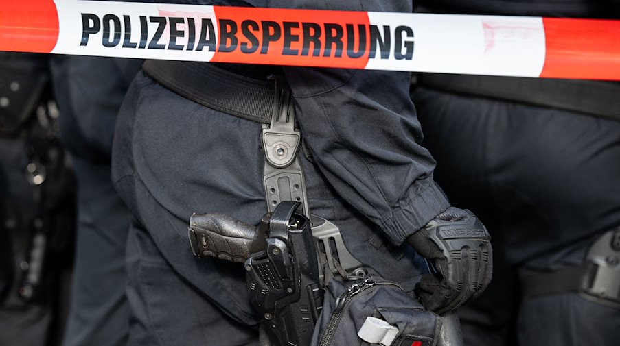 Polizisten stehen hinter einem Polizei-Flatterband. / Foto: Hannes P. Albert/dpa/Symbolbild