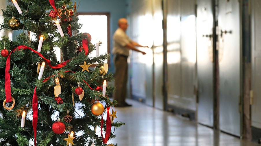 Auf einem mit einem Weihnachtsbaum geschmückten Gefängnisflur schließt ein Justizvollzugsbeamter eine Zellentür ab. / Foto: Jan Woitas/dpa-Zentralbild/dpa/Archivbild