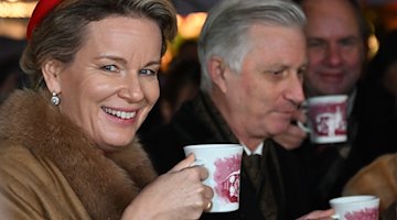 König Philippe und Königin Mathilde von Belgien trinken auf dem Weihnachtsmarkt auf dem Neumarkt Glühwein. / Foto: Robert Michael/dpa