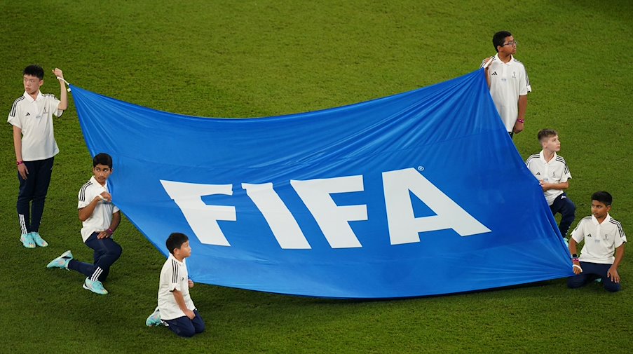 Children hold a banner with the inscription "FIFA". / Photo: Mike Egerton/Press Association/dpa