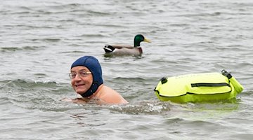 Comedian Wigald Boning schwimmt neben einer Ente in einem See. / Foto: Henning Kaiser/dpa/Archivbild