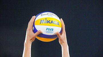 A player holds up a volleyball with both hands before the task. / Photo: Soeren Stache/dpa/Symbolic image