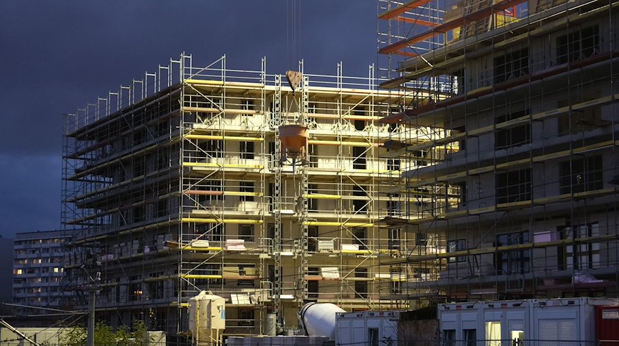 Rohbauten für Wohnhäuser werden in der Dämmerung beleuchtet. / Foto: Sebastian Willnow/dpa