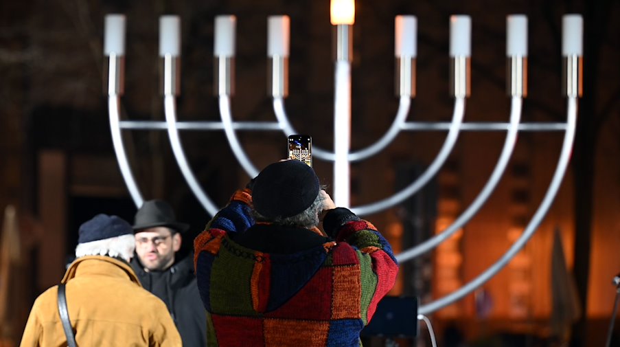 A man takes a photo of the Hanukkah candelabra before the first light is lit / Photo: Patricia Bartos/dpa