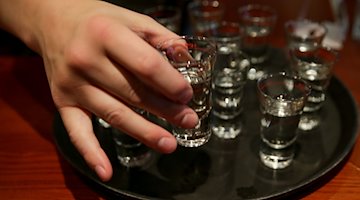 La mano de un adolescente busca un vaso de chupito lleno en un pub / Foto: Axel Heimken/dpa/Archivbild