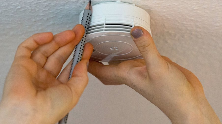 A woman marks the position of a smoke detector on the ceiling with a pencil / Photo: Patrick Seeger/dpa