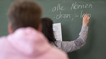 Eine Lehrerin schreibt an eine Tafel. / Foto: Marijan Murat/dpa/Symbolbild