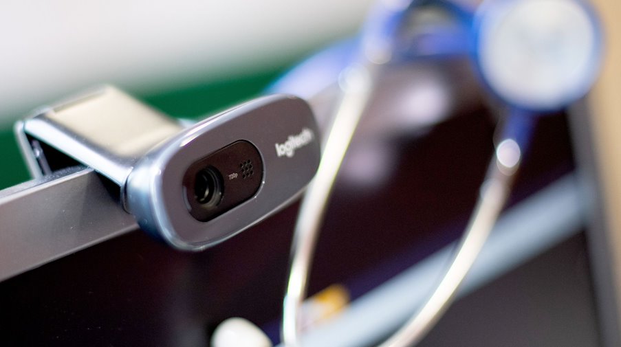 Eine Webcam und ein Stethoskop sind in einer Arztpraxis neben einem Computer bei der Videosprechstunde zu sehen. / Foto: Monika Skolimowska/dpa