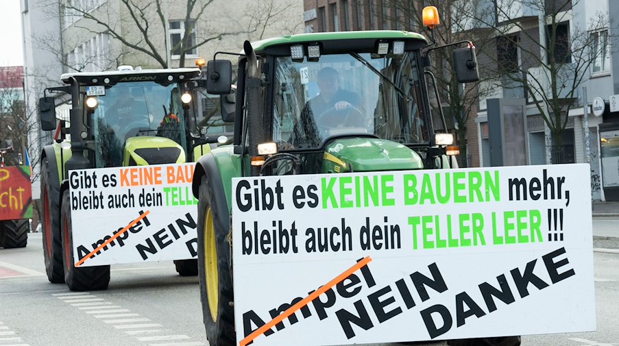 Landwirte demonstrieren mit ihren Treckern vor dem Exerzierplatz und haben Plakate mit der Aufschrift "Gibt es keine Bauern mehr, bleibt auch dein Teller leer" und "Ampel nein danke" an zwei Treckern angebracht. / Foto: Felix Müschen/dpa