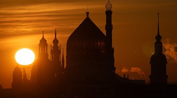 Dresdens Wahrzeichen zeichnen sich bei Sonnenaufgang als Silhouette ab. / Foto: Sebastian Kahnert/dpa/Archivbild