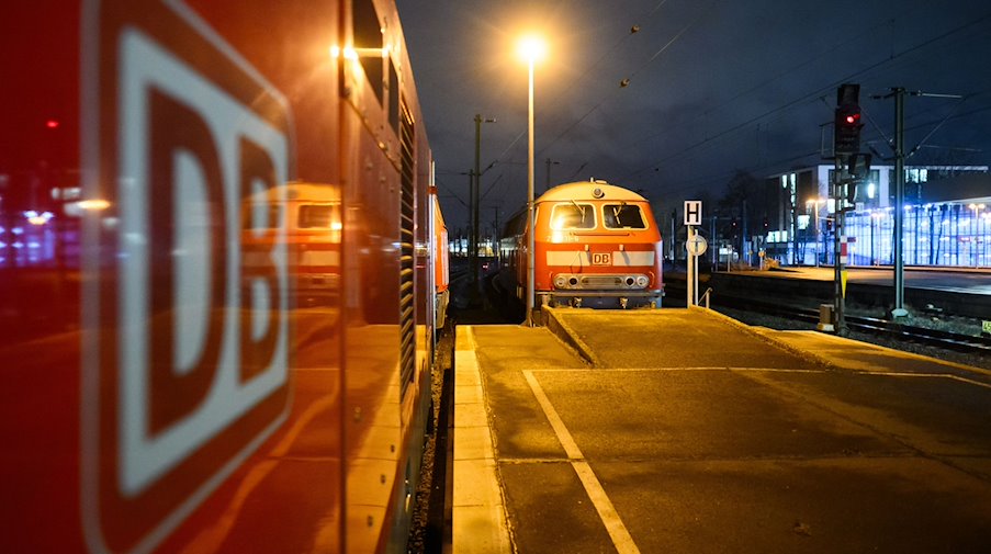 A Deutsche Bahn DB locomotive stands in a central station and is reflected in a carriage with the DB logo. / Photo: Julian Stratenschulte/dpa