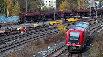 Gleisarbeiter arbeiten an Schienen, während ein Zug der Deutschen Bahn Richtung Hauptbahnhof einfährt. / Foto: Daniel Vogl/dpa/Archivbild