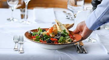 Офіціант подає тарілку салату в ресторані / Фото: Jens Kalaene/dpa/Symbolic image