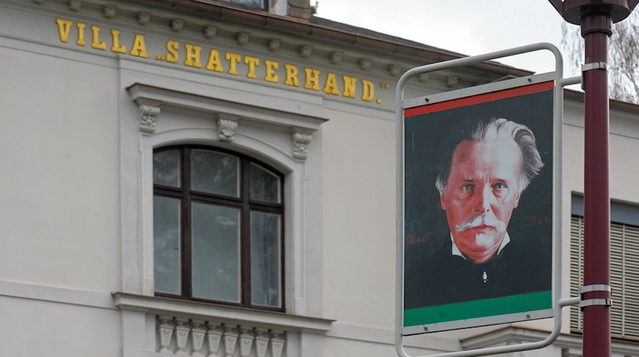 Ein Porträt des Schriftstellers Karl May hängt an einer Laterne vor dem Museum in Radebeul. / Foto: Matthias Hiekel/dpa-Zentralbild/dpa