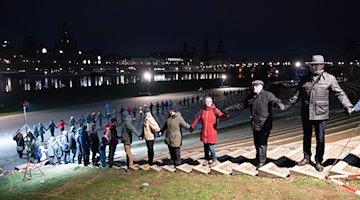 Mit einer Menschenkette wird am Königsufer der Zerstörung der Stadt im Zweiten Weltkrieg gedacht. / Foto: Sebastian Kahnert/dpa