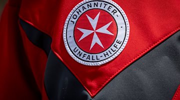 El logotipo de Johanniter-Unfall-Hilfe puede verse en la chaqueta de un portavoz de prensa. / Foto: Moritz Frankenberg/dpa