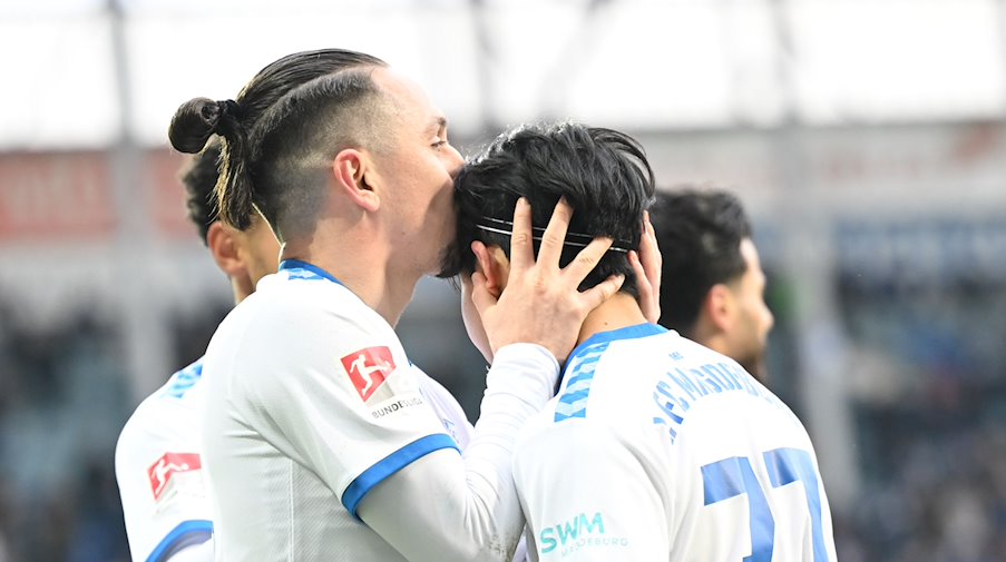 Magdeburgs Baris Atik (l) gibt Tatsuya Ito nach dem 1:0 einen Kuss auf den Kopf. / Foto: Sebastian Christoph Gollnow/dpa