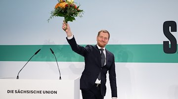 Michael Kretschmer (CDU), ministro presidente de Sajonia, sostiene un ramo de flores tras su elección en el primer puesto de la lista para las elecciones parlamentarias estatales en la reunión de representantes estatales de la CDU de Sajonia. / Foto: Sebastian Kahnert/dpa