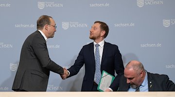 Michael Kretschmer (centro) y Wolfram Günther (izquierda) se dan la mano tras la rueda de prensa del gabinete en la Cancillería del Estado / Foto: Robert Michael/dpa