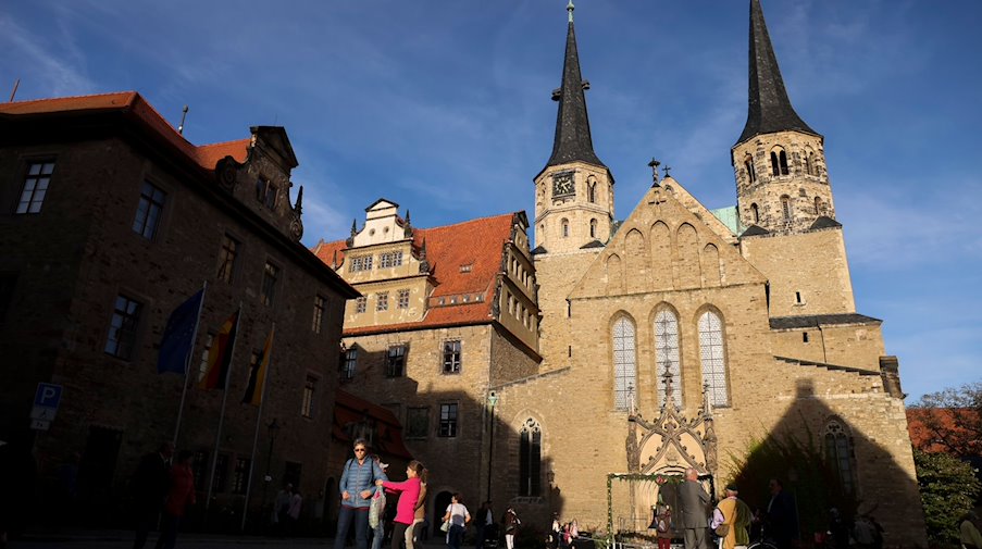 Besucher gehen vor dem Merseburger Dom nach der Weihe der neuen Glocke über den Domplatz. / Foto: Jan Woitas/dpa-Zentralbild/dpa