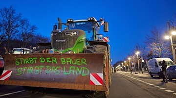 "If the farmer dies, the land dies" is written on a sign attached to a tractor. / Photo: Jörg Carstensen/dpa